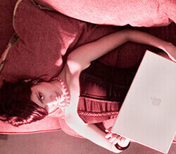 Attractive model lays on couch with computer.