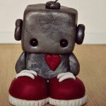A sad little robot standing on the floor.
