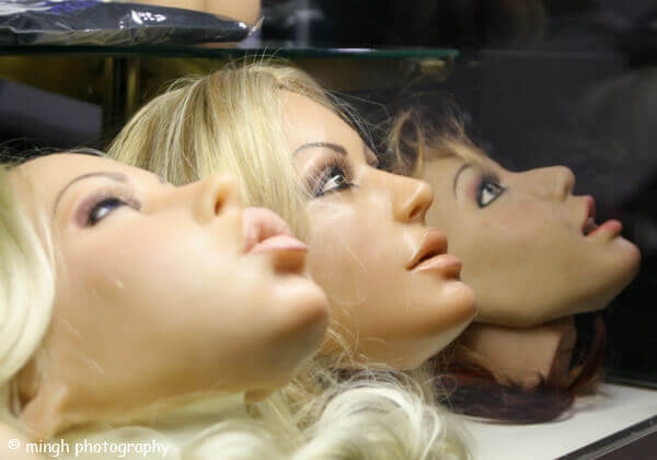 Three female sex doll heads facing up is a display case.