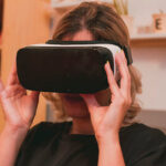 A woman sits wearing a VR headset.