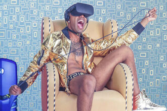 A good-looking young man sits and wears a VR headset.