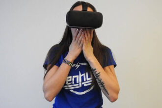 A woman wearing a VR headset covering her mouth in what looks like shock.