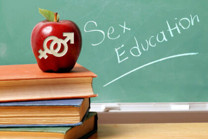An apple with male and female symbols carved into it appears in front of a chalkboard that says "Sex Education."