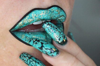 A woman with green-painted lips and nails.