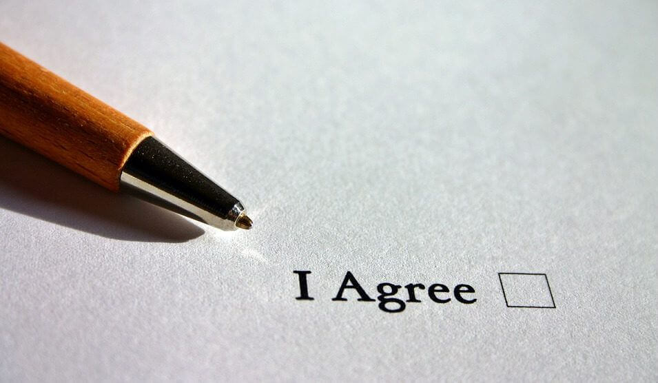 A pen lies next to a checkbox with the words "I Agree" next to it.