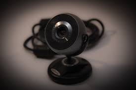 A black circular webvam on a stand appears in front of cables on a brown background.