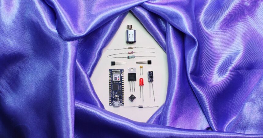 A purpe satin sheet encircles disassembled electronic parts.