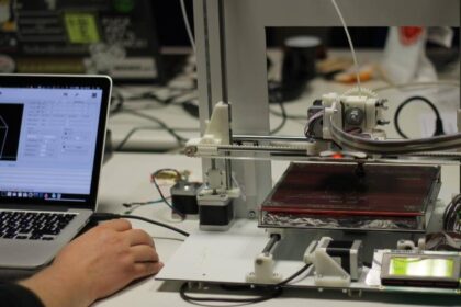 Image of a man working on laptop and 3D printer