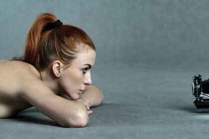Image of a naked beautiful girl lying before old camera for selfie