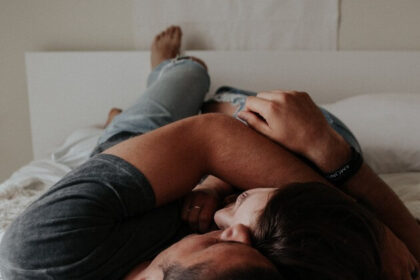 A couple cuddles on a bed