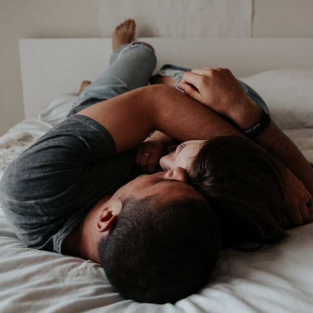 A couple cuddles on a bed