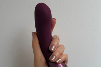 Hot Octopuss Kurve dual motor vibrator held in a white person's hand.