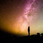 A silhouette of a person looking at the night sky.