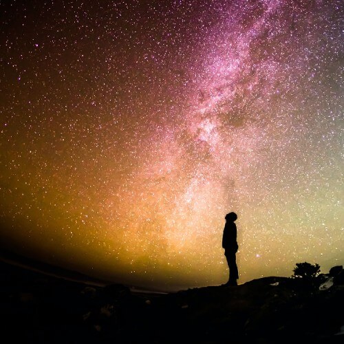 A silhouette of a person looking at the night sky.