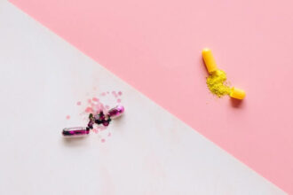 Decorative image of two pills with sparkles exploding out against a white and pink background.