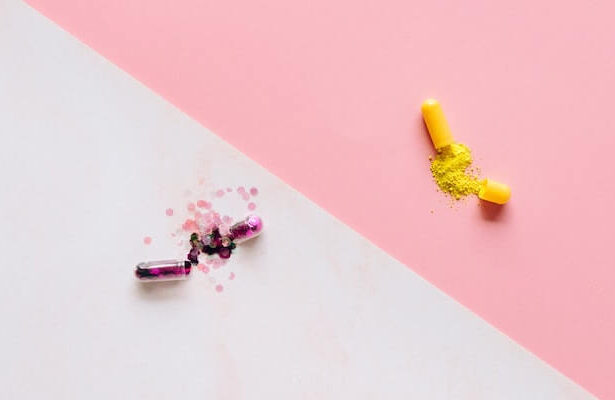 Decorative image of two pills with sparkles exploding out against a white and pink background.