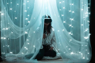 A decorative image of a woman sitting in a canopy wearing a virtual reality headset. She's surrounded by pillows and twinkly lights.