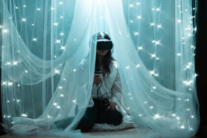 A decorative image of a woman sitting in a canopy wearing a virtual reality headset. She's surrounded by pillows and twinkly lights.