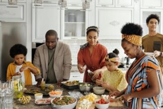 A family with four adults making dinner together with two children.