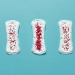 Five menstrual pads with varying degrees of red sprinkles on top to represent the various stages of periods.
