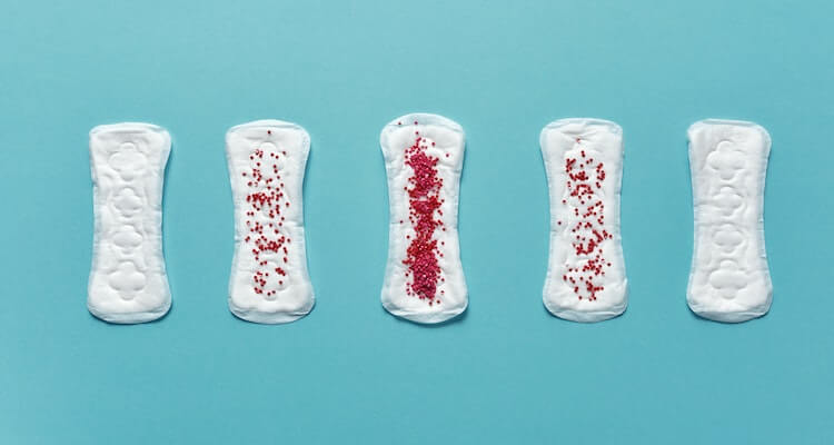 Five menstrual pads with varying degrees of red sprinkles on top to represent the various stages of periods.