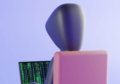 Clay-type model of a hacker in a hoodie at a desk. On the screen you see the stereotypical green code.
