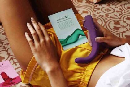 A woman lying her back holding the Crescendo 2 with a pamphlet with various positions for how to use it.