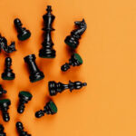 Black chess pieces laying across an orange background.