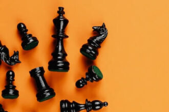 Black chess pieces laying across an orange background.