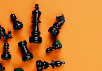 Black chess pieces laying across an orange background.