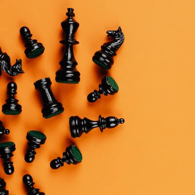 Black chess pieces laying across an orange background.