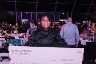 Glenise holding a check for $250,000.