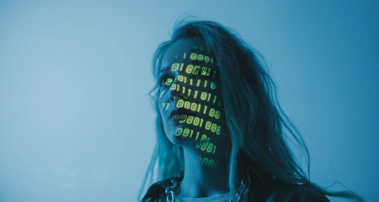 Woman in blue lighting with yellow binary code projected across her face.