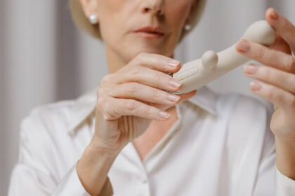 An older woman holding white vibrator, the camera focused on her hands.