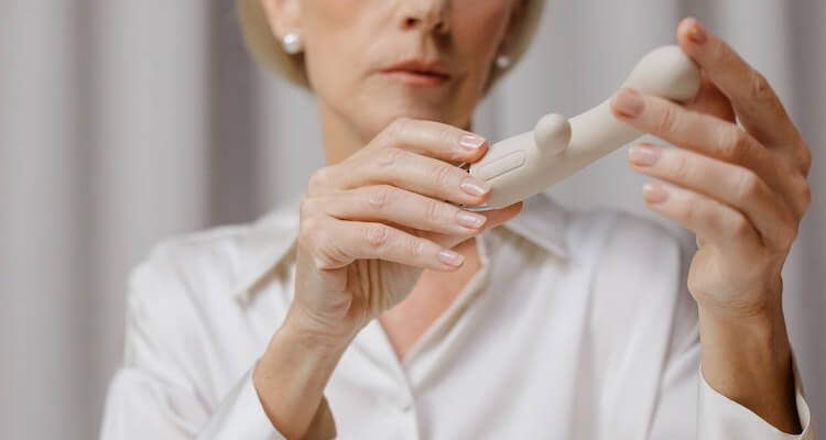 An older woman holding white vibrator, the camera focused on her hands.